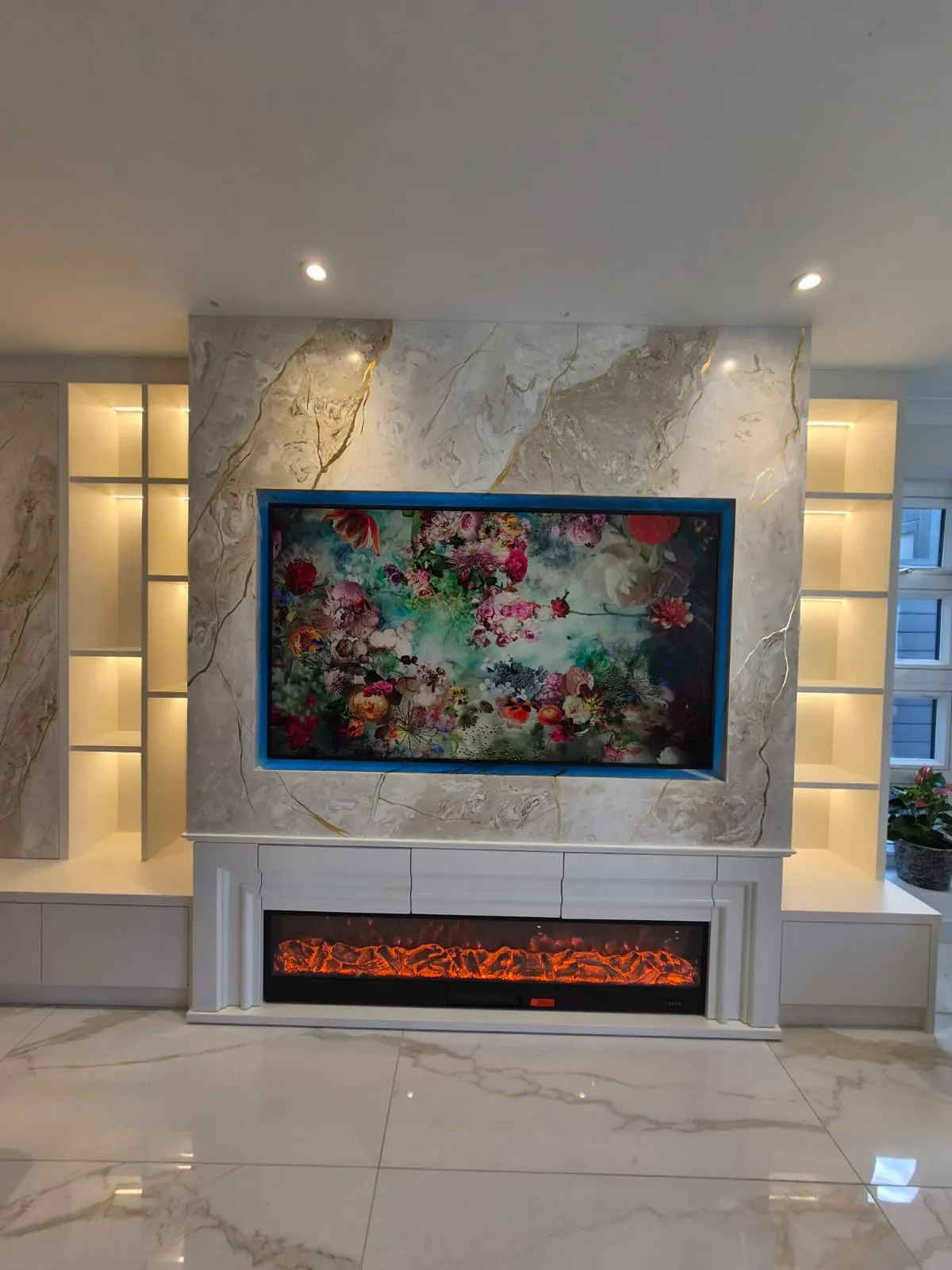After: the same wall with the same fireplace, now set into a full height Venetian plaster media wall with the TV recessed above the fire