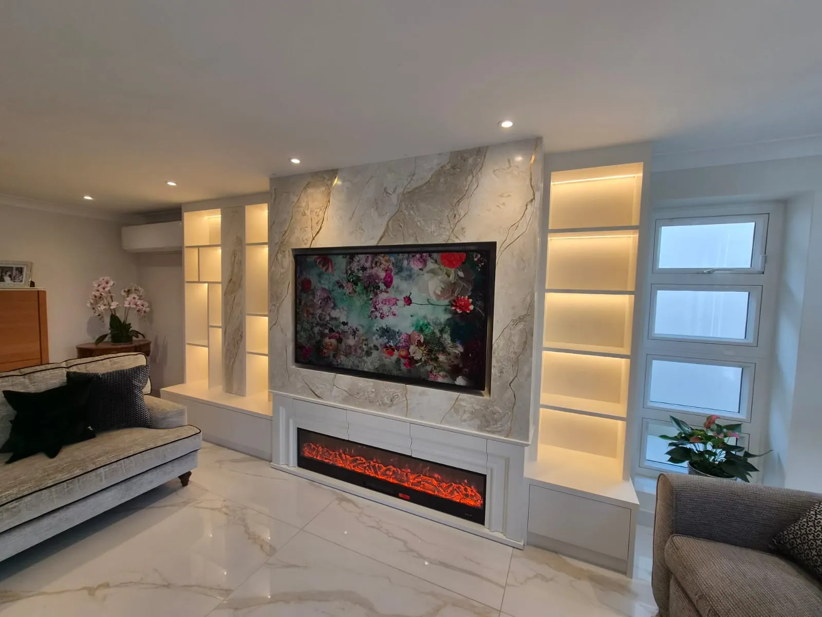 Finished Venetian plaster media wall in a Hertfordshire living room, with the retained linear fire, recessed TV and lit shelving either side